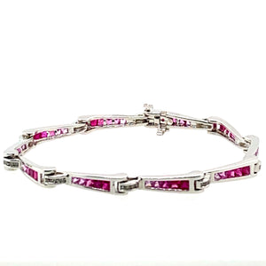 Show off your sophisticated style with this 18 Karat White Gold Bracelet. Each link graduates in color from Genuine Ruby gemstones to Pink Sapphire Gemstones totaling 3.00 total Carats. the bracelet holds even more sparkle with .33ctw of Diamonds. The hidden safety provides that extra security.  Length is 7"  Total weight is 14.9 Grams  