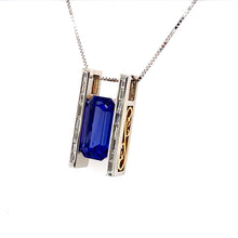 Load image into Gallery viewer, Mined in Tanzania, this Gemstone is known to align the Heart and the Mind. This Gorgeous Pendant Showcases a 12.16 Carat Deep Violet Blue Tanzanite Gemstone. Custom Made in 18 Karat White Gold with Yellow Gold Accents on the Sides, Baguette-Cut Diamonds going down each side gives it that extra sparkle.