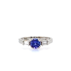 This Beautiful Round Blue-Purple .60 Carat Tanzanite Gemstone is Beautifully Set in Polished 18 Karat White Gold with a Tapered Baguette Diamond on Each Side.  Total Diamond Weight .25dtw  Total Weight 3.5 Grams  Finger Size 7 