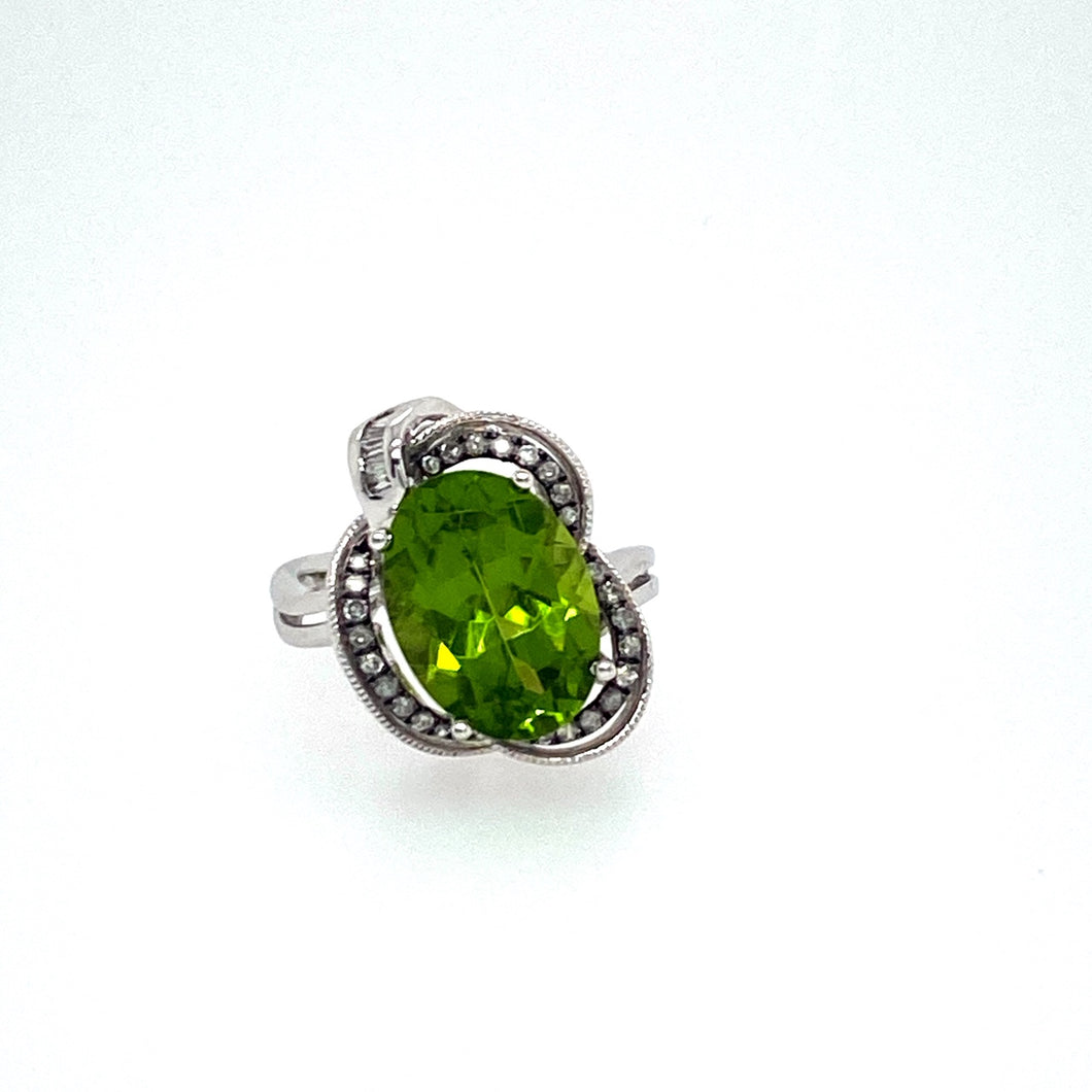 A Unique 14 Karat White Gold Designed Ring is Holding this 6.74 Carat Oval Peridot Gemstone with Some Sparkling Diamonds set around it.  Total Diamond Weight .29dtw  Total Weight 5.9 Grams  Finger Size 7