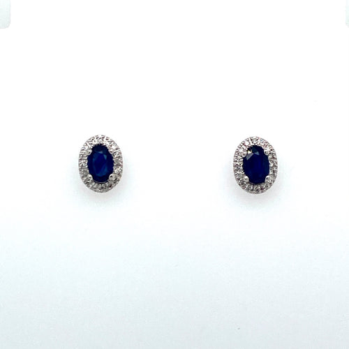 This Pretty Little Pair of 14 Karat White Gold Stud Earrings Feature an Oval Blue Sapphire Gemstone Embellished with a Diamond Halo.  The Earrings are Secured with Posts and Push on Backs.  Total Sapphire Gemstone Weight is 1.04 Carat 