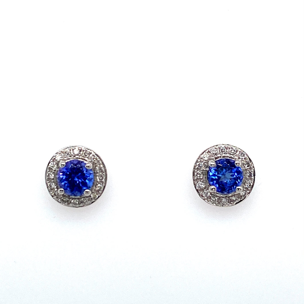 Magnificent Bold Blue Color best Describes these 14 Karat White Gold Round Tanzanite Gemstone Stud Earrings. Each Earring Features a 1 Carat Tanzanite Gemstone surrounded in a Round Diamond Halo Setting.  The Earrings are Secured with Posts and Push on Backs.  Total Gemstone Weight 2.05 Carats  Total Diamond Weight .25 Carat
