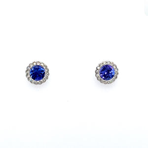 This Pair of 14 Karat White Gold Round Stud Earrings Feature a Rippled Setting with a Gorgeous Round Blue-Purple Tanzanite Gemstone set in the Center with a Diamond Halo. The Earrings are Secured with Posts and Push on Backs.  Total Gemstone Weight 1.11 Carats  Total Diamond Weight .23 Carat