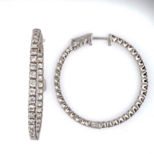 These 14 Karat White Gold Round Hoop Earrings Feature 1.40 Diamond Total Weight of Round Diamonds set Inside and Outside of the Earring. The Earrings Feature a Push Down Click in Closure.