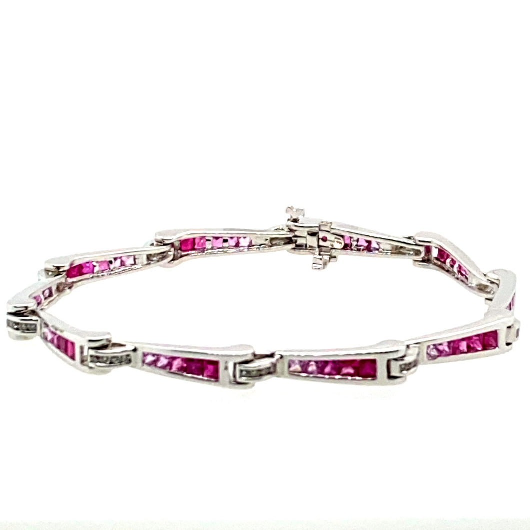 Show off your sophisticated style with this 18 Karat White Gold Bracelet. Each link graduates in color from Genuine Ruby gemstones to Pink Sapphire Gemstones totaling 3.00 total Carats. the bracelet holds even more sparkle with .33ctw of Diamonds. The hidden safety provides that extra security.  Length is 7