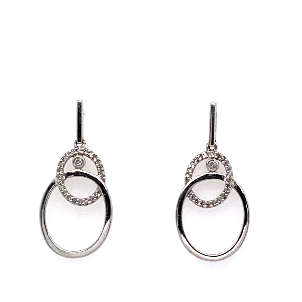 This Pair of 14 Karat White Gold Estate Earrings Feature a Double Oval Dangle. The Bottom Larger Oval is High Polished White Gold while the Top Smaller Oval Dangle Features Prong set Diamonds, and a Bezel set Diamond at the Top .  the Earrings are Secured with Posts and Push on Backs.  Total Weight 2.9 Grams 
